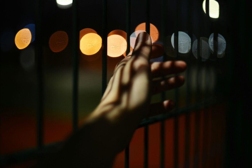A hand reaches out over a fence, creating a sense of suspense and anticipation in the scene.
