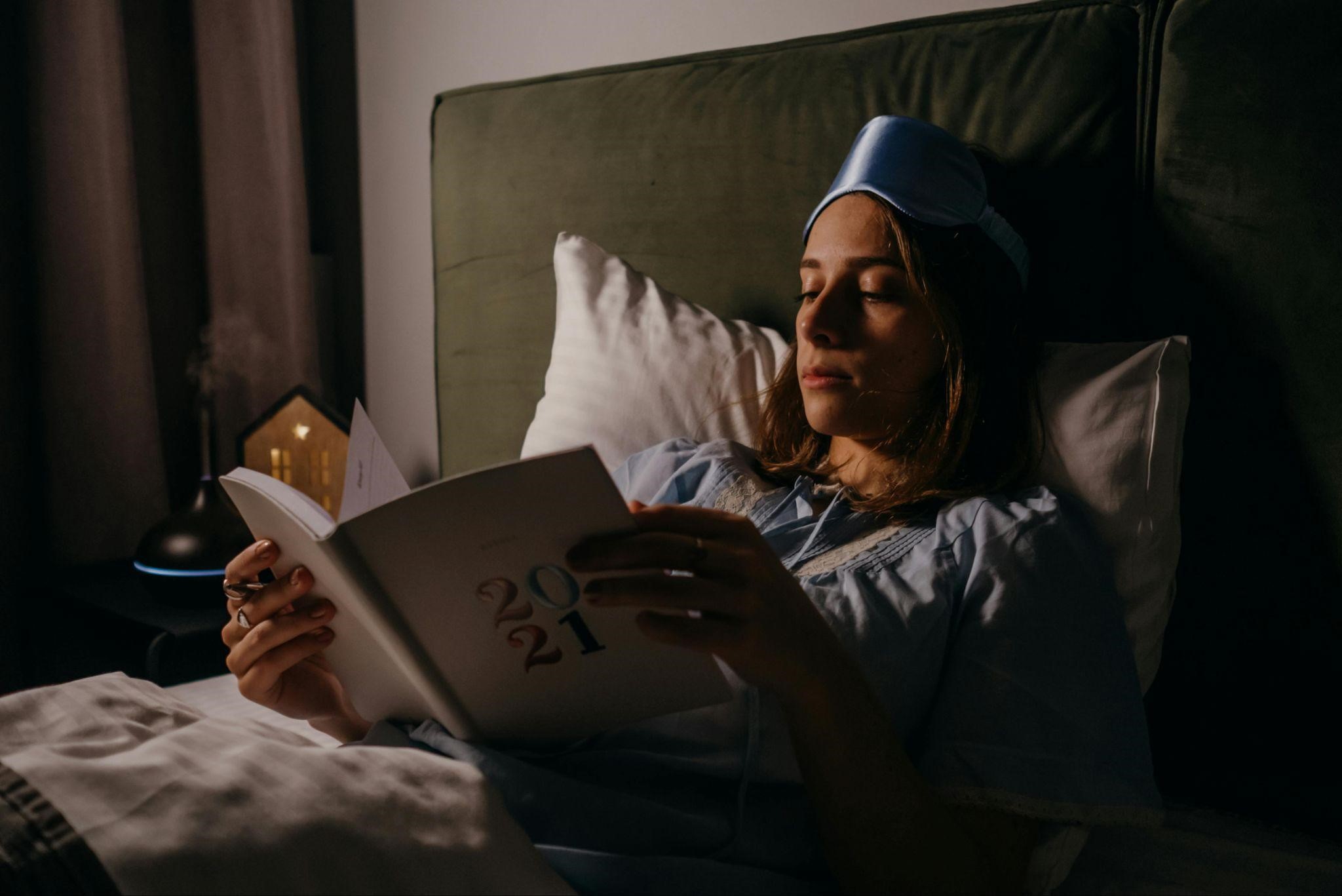 A girl reading a book in bed, symbolizing why escape thrillers keep us reading all night.