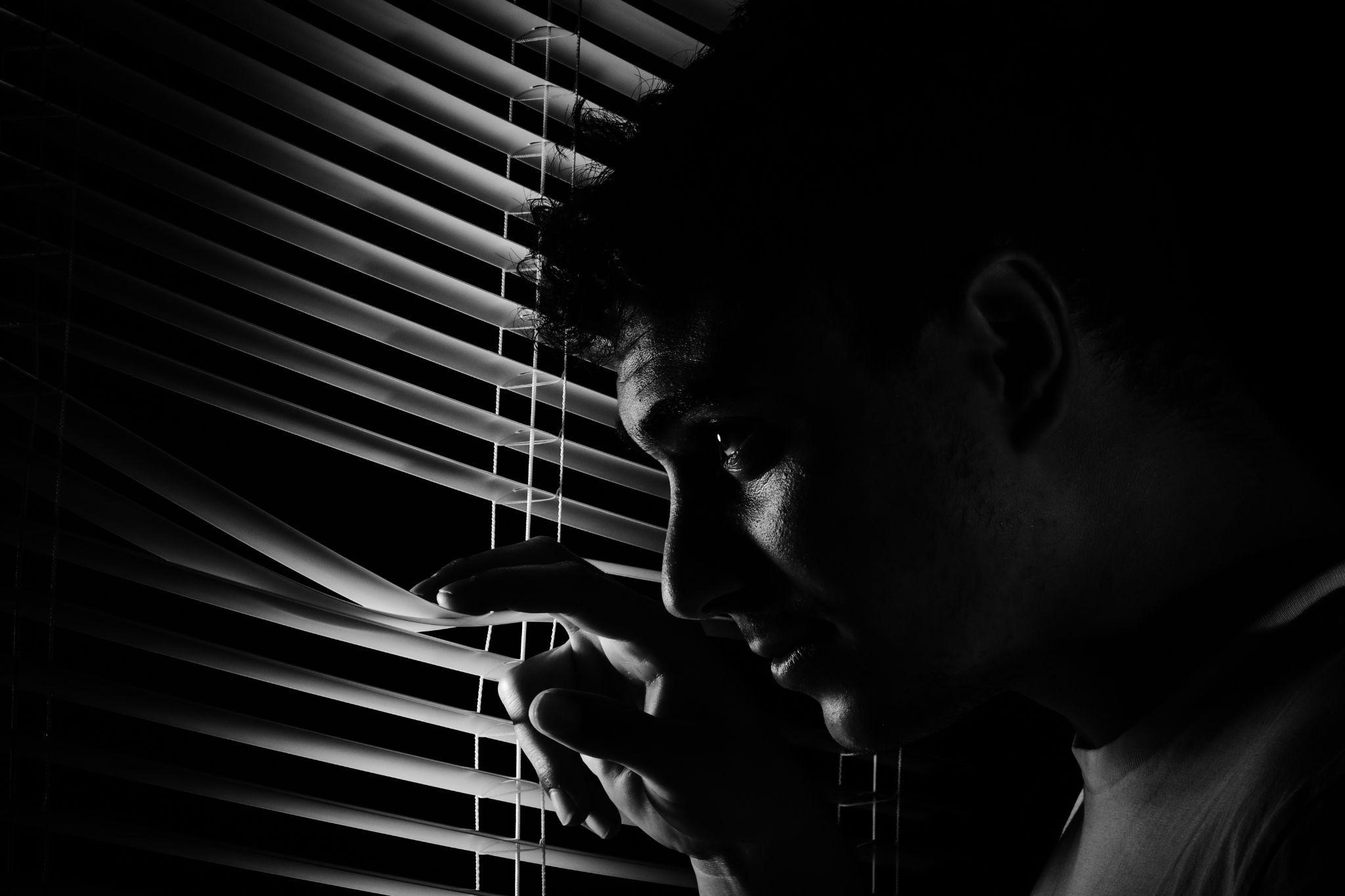 davidstewartmonth4gw2 A silhouetted man peers through blinds, showcasing how suspense novels keep readers hooked.