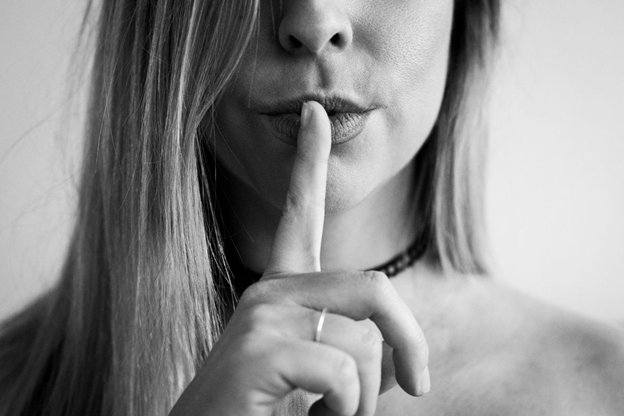 Black-and-white close-up of a woman holding a finger to her lips.